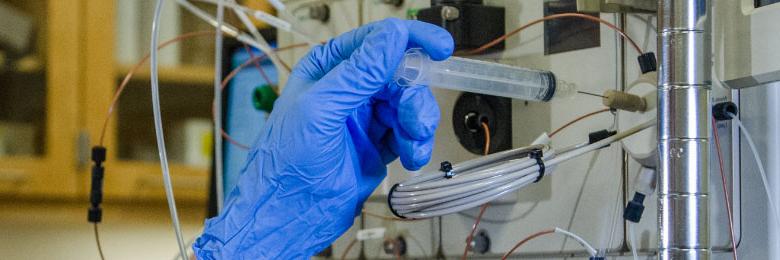 hand with syringe putting into pharmacy equipment